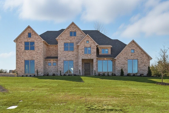 view of front of house featuring a front yard, a shingled roof, and brick siding
