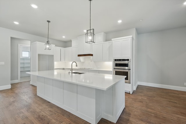 kitchen with stainless steel double oven, decorative backsplash, white cabinets, a sink, and baseboards