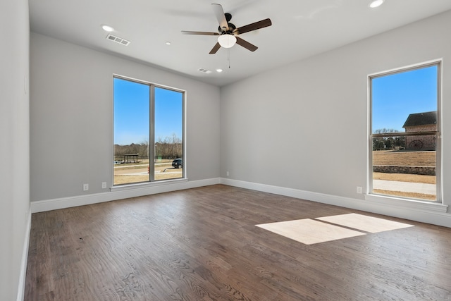 empty room with wood finished floors, ceiling fan, and plenty of natural light