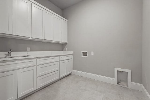 clothes washing area featuring a sink, hookup for a washing machine, cabinet space, and baseboards