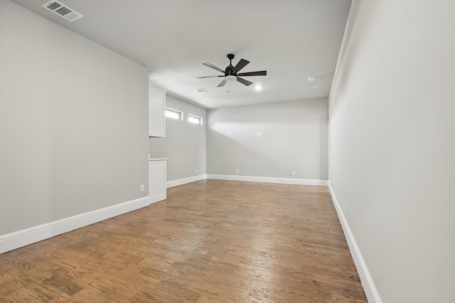 empty room with baseboards, visible vents, a ceiling fan, and light wood-style flooring