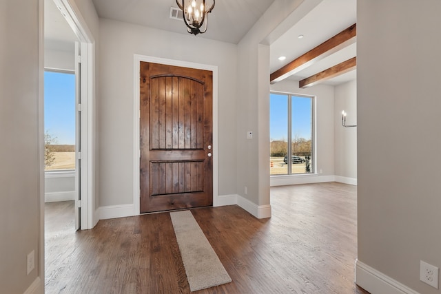 entrance foyer with wood finished floors, plenty of natural light, visible vents, and baseboards