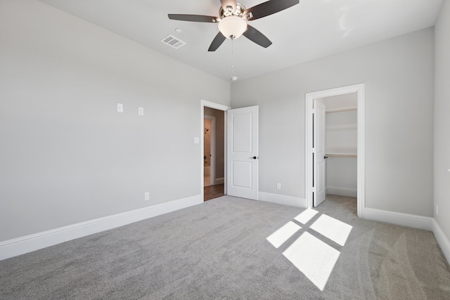 unfurnished bedroom with ceiling fan, visible vents, baseboards, carpet floors, and a spacious closet