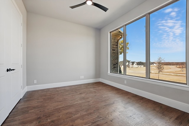 spare room with baseboards, a ceiling fan, and dark wood finished floors