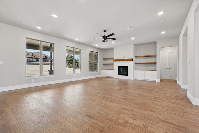 unfurnished living room featuring recessed lighting, light wood-style floors, a glass covered fireplace, a ceiling fan, and baseboards