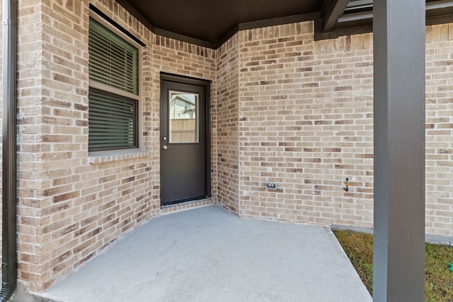 entrance to property with a patio and brick siding