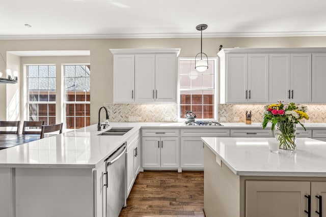 kitchen with pendant lighting, dark wood finished floors, crown molding, stainless steel appliances, and a sink