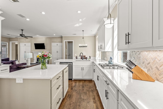 kitchen featuring appliances with stainless steel finishes, open floor plan, a peninsula, a sink, and backsplash