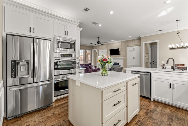 kitchen with visible vents, a center island, stainless steel appliances, crown molding, and a sink