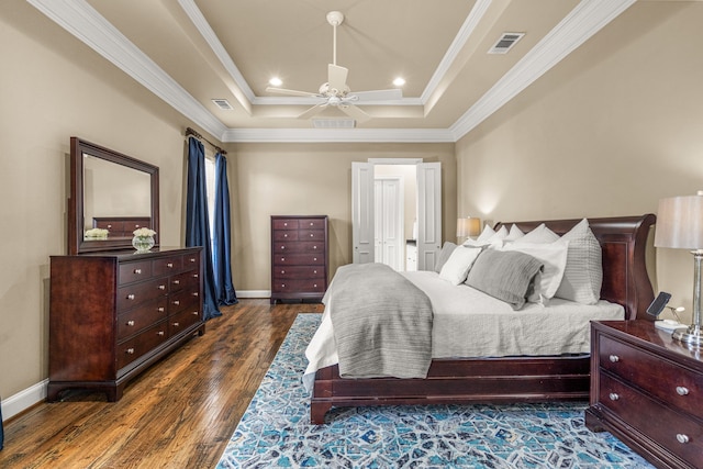 bedroom featuring crown molding, a raised ceiling, visible vents, wood finished floors, and baseboards