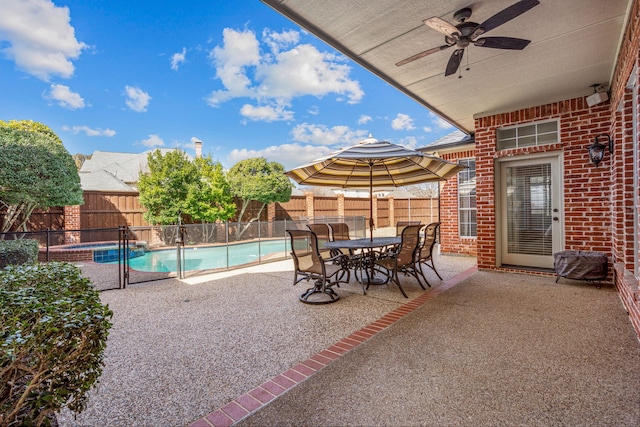 view of patio / terrace featuring ceiling fan, a pool with connected hot tub, a fenced backyard, and outdoor dining space