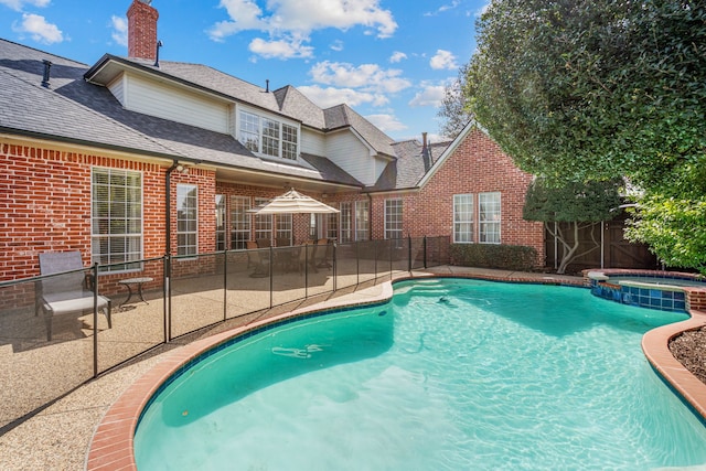 view of pool with a patio area, a pool with connected hot tub, and fence