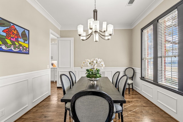 dining space with crown molding, visible vents, a notable chandelier, and wood finished floors