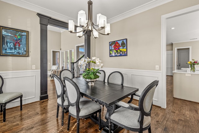 dining area with crown molding, a wainscoted wall, wood finished floors, and a notable chandelier