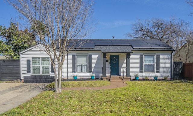 view of front of home featuring solar panels, a front lawn, and fence