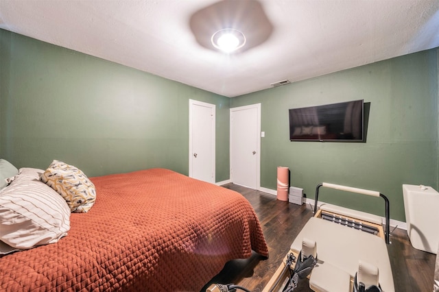 bedroom featuring wood finished floors, visible vents, and baseboards