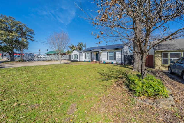 ranch-style home with a front yard, fence, driveway, and solar panels