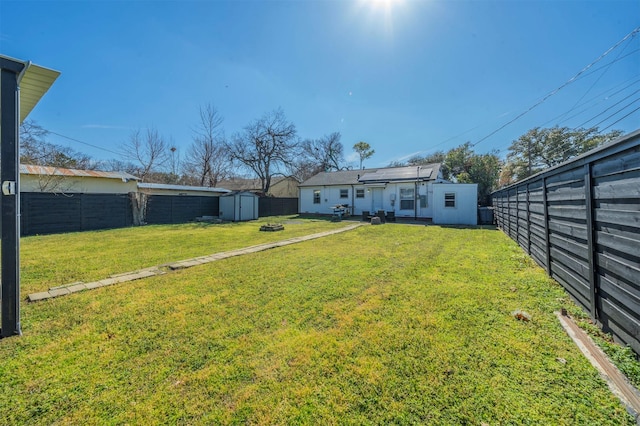 view of yard featuring a storage shed, an outdoor structure, and a fenced backyard