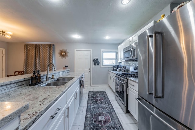 kitchen featuring appliances with stainless steel finishes, white cabinetry, a sink, and backsplash