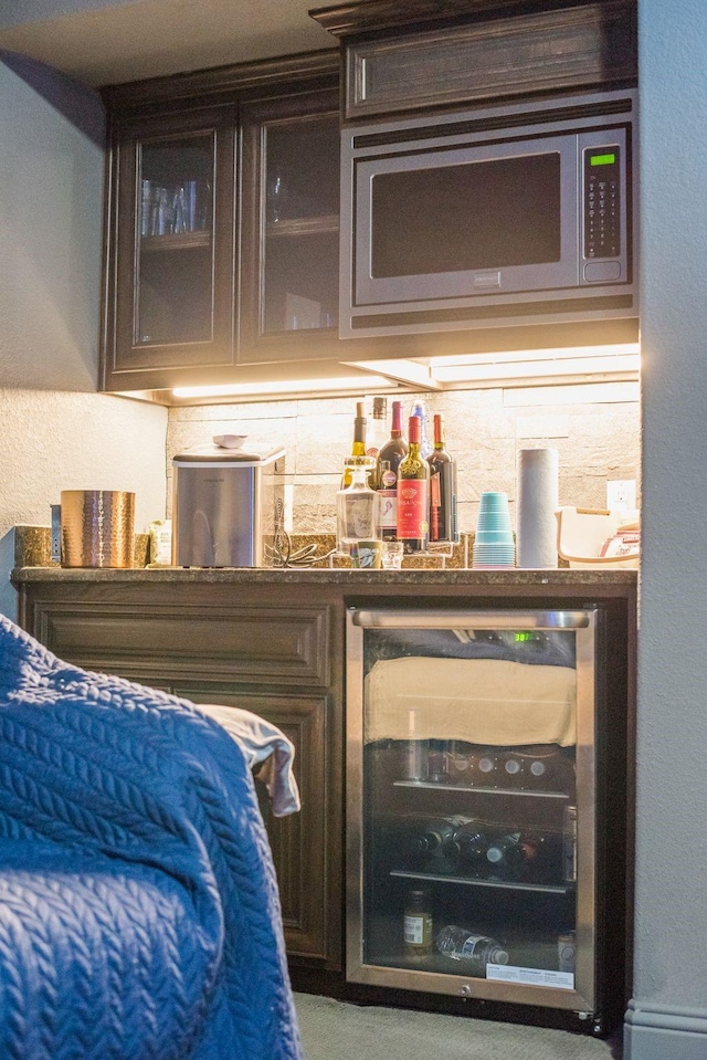 bar featuring wine cooler, stainless steel microwave, and a dry bar