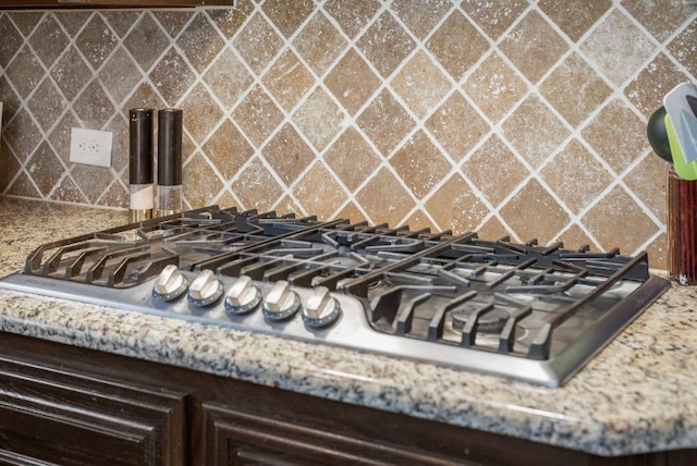 room details featuring dark brown cabinetry, stainless steel gas cooktop, and backsplash