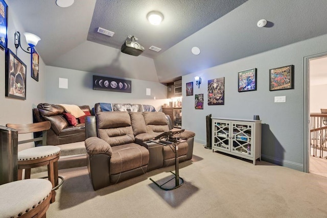 carpeted cinema featuring baseboards, visible vents, vaulted ceiling, and a textured ceiling