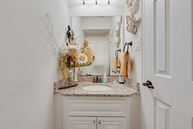 bathroom with vanity and a textured wall