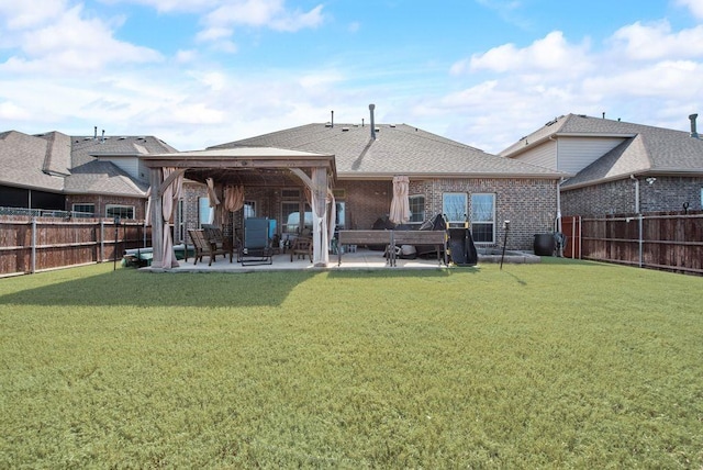 rear view of property featuring a shingled roof, a lawn, a fenced backyard, a patio area, and brick siding