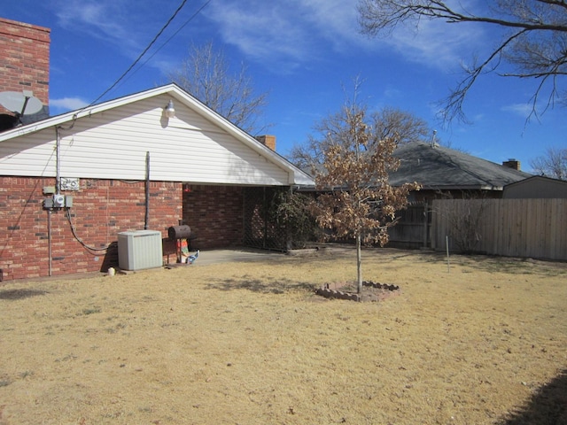 view of side of home with fence, central AC, and brick siding