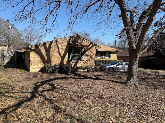 view of property exterior featuring fence and brick siding