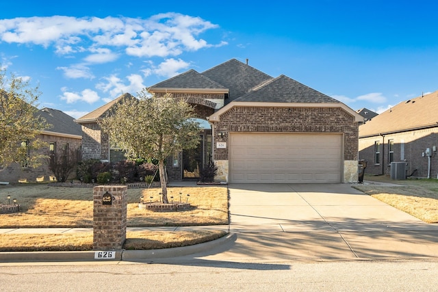 view of front of property featuring a garage, a shingled roof, concrete driveway, central AC, and brick siding