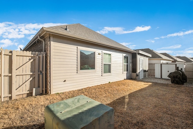 back of property featuring a gate, roof with shingles, and fence