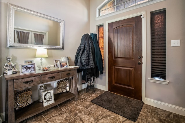 entryway with dark tile patterned floors and baseboards