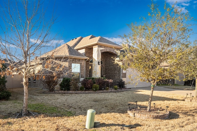 view of front of property featuring a garage, brick siding, fence, concrete driveway, and roof with shingles