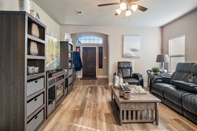 living room featuring ceiling fan, light wood-style flooring, visible vents, and baseboards