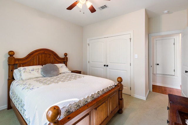 bedroom with a closet, light colored carpet, visible vents, a ceiling fan, and baseboards