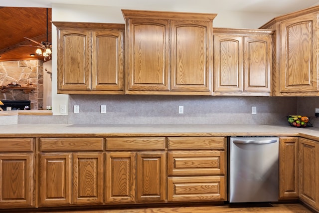 kitchen with a fireplace, tasteful backsplash, light countertops, brown cabinetry, and dishwasher