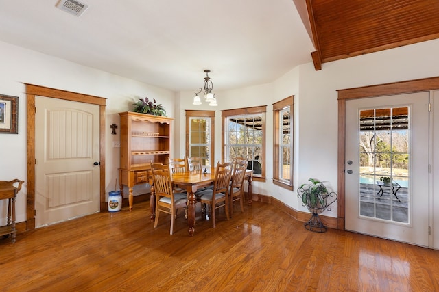 dining area featuring baseboards, light wood-style flooring, visible vents, and a notable chandelier