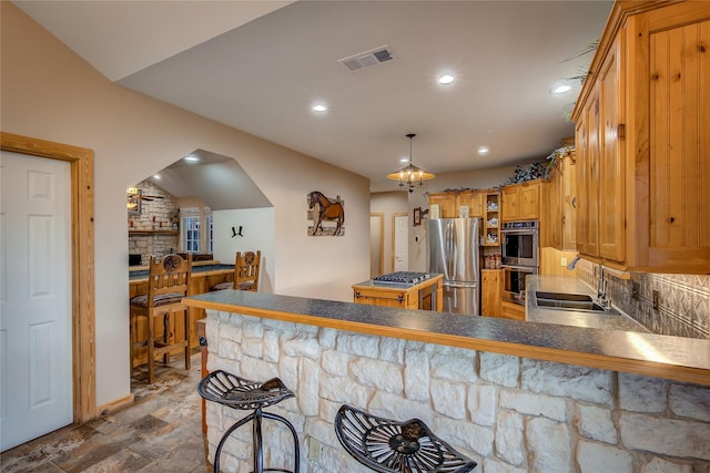 kitchen featuring a sink, stainless steel appliances, a peninsula, a kitchen bar, and visible vents