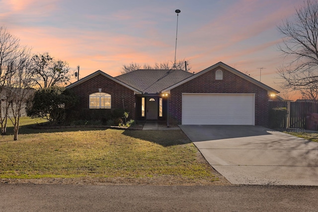 ranch-style house featuring a garage, a yard, brick siding, and driveway