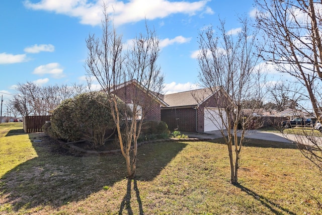 view of front facade with driveway, brick siding, an attached garage, fence, and a front yard