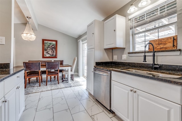 kitchen featuring dark stone countertops, marble finish floor, vaulted ceiling, stainless steel dishwasher, and a sink