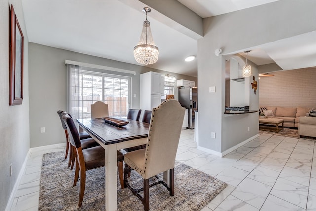 dining space with marble finish floor, an inviting chandelier, brick wall, and baseboards