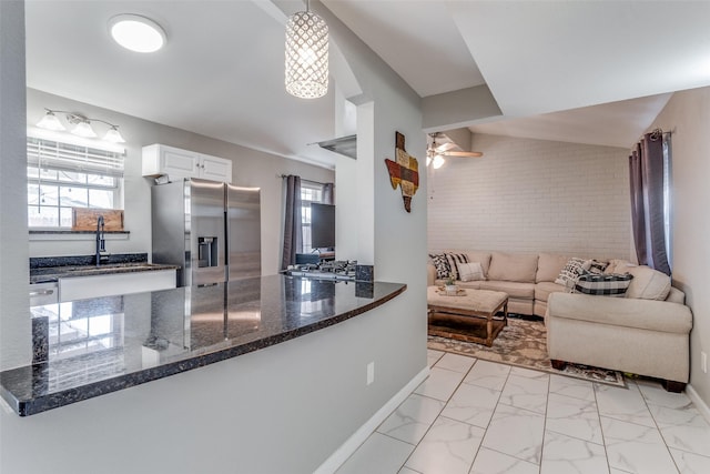 kitchen with white cabinets, marble finish floor, stainless steel refrigerator with ice dispenser, stovetop, and dark stone countertops