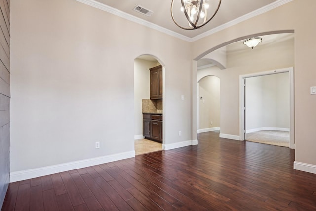 empty room featuring baseboards, visible vents, ornamental molding, wood finished floors, and an inviting chandelier