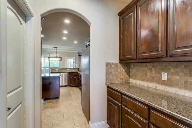 kitchen featuring stainless steel appliances, arched walkways, stone countertops, and tasteful backsplash