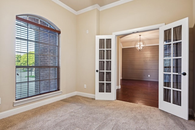 unfurnished room with baseboards, ornamental molding, an inviting chandelier, french doors, and carpet floors