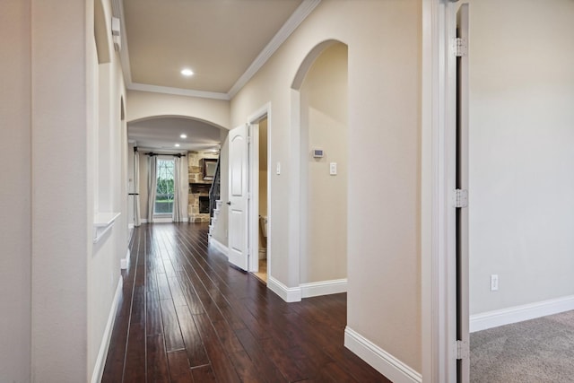 corridor featuring arched walkways, crown molding, dark wood finished floors, recessed lighting, and baseboards