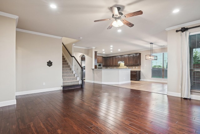 unfurnished living room featuring baseboards, stairway, wood finished floors, and crown molding