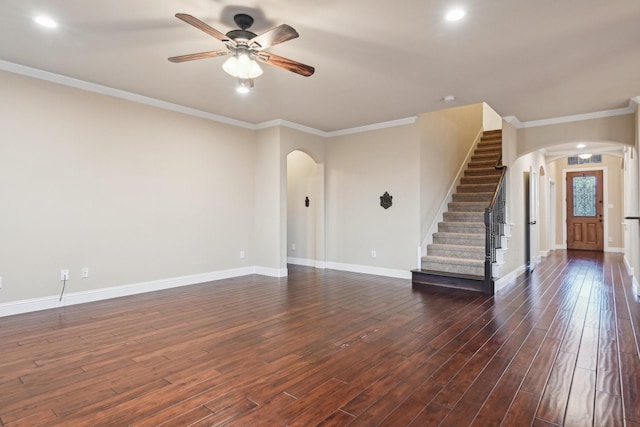 unfurnished living room with arched walkways, dark wood finished floors, ornamental molding, baseboards, and stairs